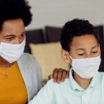 Black mother son using laptop while homeschooling during coronavirus epidemicd